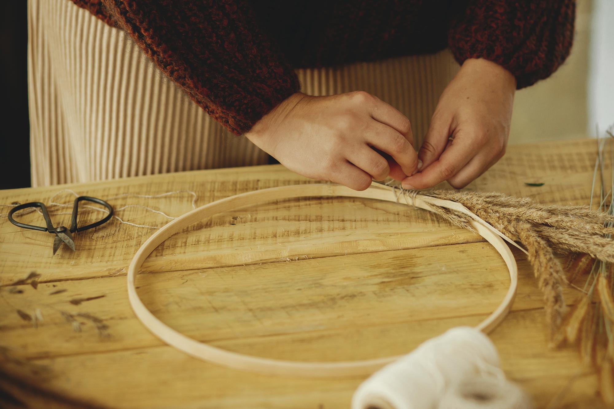 Close-up of hand-guided embroidery hoop with gold thread
